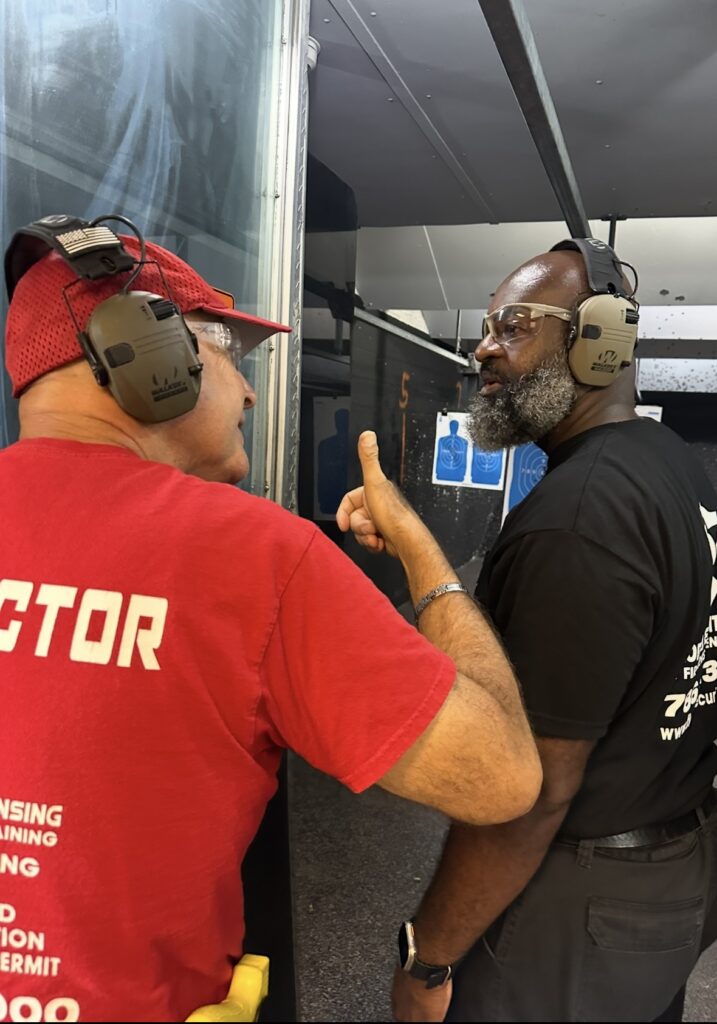 Firearms instructor pointing out vital safety information to a student at the shooting range during training.